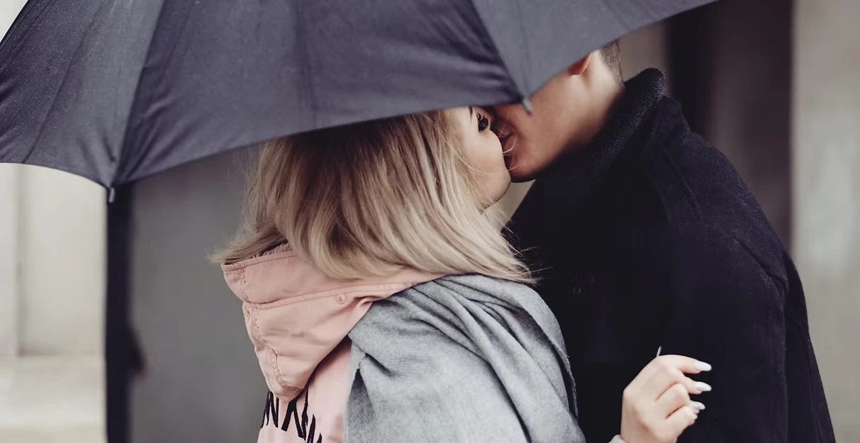 A couple in close embrace beneath an umbrella — connection through real moments